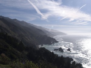 Photo of the Big Sur, California coastline showing the line of the hills angling down to the ocean and the light shining on the hillside